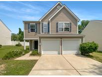 Two-story home with a two-car garage, tan siding, blue shutters, and manicured lawn on a clear day at 735 Sycamore Springs Dr, Fuquay Varina, NC 27526
