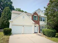 Two-story home with a two-car garage, and brick and cream-colored siding at 107 Woolard Way, Apex, NC 27502