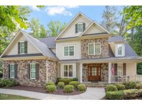 Charming stone and siding home featuring manicured landscaping and a welcoming front porch at 286 Harrison Pond Dr, Pittsboro, NC 27312