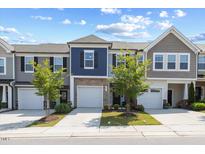 Attractive townhomes with garages and manicured lawns under a partly cloudy sky at 44 Bordeaux Dr, Clayton, NC 27527