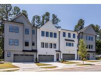 Modern townhomes feature varied exteriors, private garages, and manicured lawns against a blue sky at 4502 Mint Leaf Ln, Raleigh, NC 27612