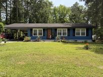 Charming blue single-story home featuring a lush front yard and covered carport at 509 Forest Ridge Rd, Garner, NC 27529