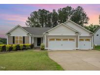 Charming single-story home featuring a two-car garage and a well-manicured front lawn at 65 Cattail Ln, Zebulon, NC 27597