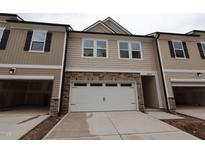 New two-story townhouse with neutral siding, stone accents, attached two-car garage and driveway at 6973 Doddridge Ln # 17, Cary, NC 27519