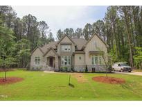 A traditionally styled home features a stone entryway and a well-manicured lawn surrounded by mature trees at 1212 Perry Bluff Dr, Wake Forest, NC 27587
