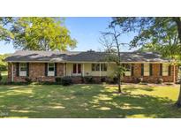 Charming single-story brick home featuring a lush front yard and a welcoming red double-door entrance at 129 Castle Dr, Smithfield, NC 27577