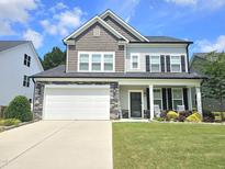 Charming two-story home featuring a well-manicured lawn and a stone-accented facade with a two-car garage at 1412 Queen Trigger Dr, Fuquay Varina, NC 27526