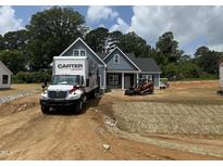 New construction home with blue siding, landscaping, and a Carter Lumber truck in the driveway at 183 Tee Dr, Selma, NC 27576