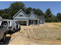 Charming home featuring hardiplank siding, an attached garage, and a covered front porch in a partially cleared lot at 183 Tee Dr, Selma, NC 27576