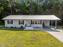 Charming one-story white brick home featuring a metal roof, well-manicured lawn, and an attached carport at 2210 Pilot-Riley Rd, Zebulon, NC 27597