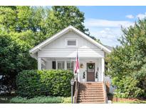 Charming white cottage with brick steps, lush landscaping, and an American flag at 2225 Creston Rd, Raleigh, NC 27608