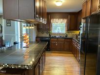 Well-lit kitchen features wood cabinets, black appliances, and a large island with seating at 3298 Oakridge Dr # A, Graham, NC 27253