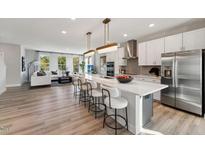Bright kitchen with white cabinets, stainless steel appliances, and a large island with seating at 404 Gaston Park Ln # 200, Wake Forest, NC 27587
