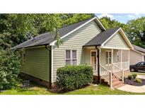 Charming home featuring light green siding, a dark roof, and a classic front porch entry at 413 Top Greene Ln, Raleigh, NC 27601