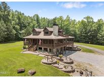 Stunning, elevated log home with stone chimney, wraparound porch, and beautifully landscaped yard at 4659 Antioch Rd, Oxford, NC 27565