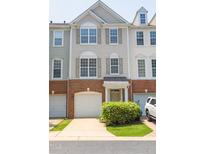 Attractive three-story townhome featuring an attached garage, brick accents, and a well-maintained lawn and garden at 4933 Wyatt Brook Way, Raleigh, NC 27609