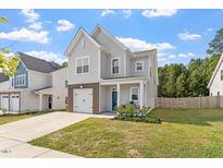 Charming two-story home with gray siding, brick accents, a well-manicured lawn, and a cozy front porch at 6512 Bunker Hill Dr, Raleigh, NC 27610