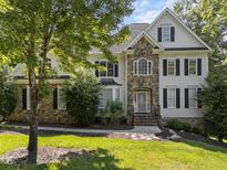 Charming two-story home featuring stone accents, black shutters, and a well-manicured lawn at 7000 Millstone Ridge Ct, Raleigh, NC 27614