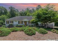 Charming single-story home with black shutters, wrought iron fence and lush landscaping at 877 Millcroft, Pittsboro, NC 27312