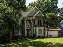 Beautiful brick two-story home featuring an attached two car garage and manicured lawn and mature trees at 109 N Fern Abbey Ln, Cary, NC 27518