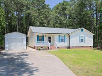 Charming single-story home with white siding, blue shutters, and a detached garage at 117 Renee Dr, Smithfield, NC 27577