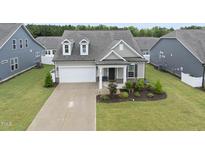 Charming home with a well-manicured lawn, inviting porch and an attached two-car garage at 129 Alumroot Rd, Holly Springs, NC 27540