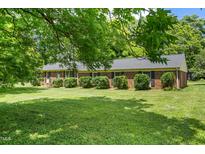 Charming brick home features a well-manicured lawn and mature trees, offering a serene and inviting curb appeal at 250 Dixon Rd, Graham, NC 27253