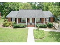 Charming brick home featuring a well-manicured front lawn and an inviting covered porch at 303 Spring St, Louisburg, NC 27549