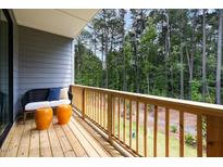 View of a cozy balcony with wooded view, stylish seating, and modern orange accent stools at 4713 Mint Leaf Ln, Raleigh, NC 27612