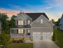 Charming two-story home with a welcoming front porch, stone accents, and a well-manicured lawn under a beautiful sky at 525 Marion Hills Way, Knightdale, NC 27545