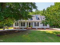 Traditional-style home featuring a well-manicured lawn, mature trees, dormers, and charming curb appeal at 5413 Lower Creek Ct, Apex, NC 27539