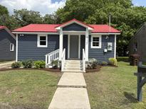 Charming home featuring gray siding, a red roof, and a welcoming front entrance with landscaped yard at 713 Champion St, Henderson, NC 27536