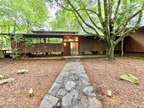 Stunning exterior view of a mid-century modern home with a stone pathway and wooded surroundings at 808 Indian Springs Rd, Chapel Hill, NC 27514