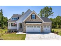 Beautiful stone and siding exterior with a three-car garage and well-manicured lawn at 98 Priming Way, Angier, NC 27501
