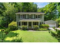 Charming two-story home featuring a well-manicured lawn, mature trees, and a detached garage at 1006 Apache Ln, Apex, NC 27502