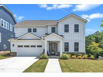 Charming two-story white home featuring a two-car garage, well-manicured lawn, and sidewalk leading to the front porch at 109 Crested Coral Dr, Holly Springs, NC 27540