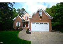 Charming brick home with a manicured lawn, red door, two-car garage, and colorful flower boxes at 111 Ferncroft Ct, Cary, NC 27519