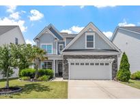 Charming two-story home with a two car garage, stone accents, manicured lawn, and mature landscaping at 1161 Tulip Poplar Rd, Fuquay Varina, NC 27526