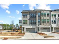 Modern townhome featuring a two-car garage, neutral-toned siding, and an inviting entryway in a residential neighborhood at 1203 Corkery Ridge Ct, Cary, NC 27519