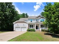 Charming two-story home with a covered front porch, a two-car garage, and a well-manicured lawn at 1304 Double Oak Ln, Willow Springs, NC 27592