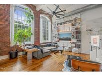Inviting living room with exposed brick, large windows, and a stylish shelving unit at 1535 Caraleigh Mills Ct # 210, Raleigh, NC 27603
