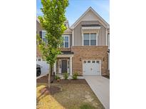 Beautiful brick townhome with an attached garage and gray siding, complemented by a well-maintained lawn at 214 George Pine Way, Knightdale, NC 27545