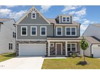 Charming two-story home with a stone facade, attached garage, and manicured lawn at 311 Horseshoe Pl, Angier, NC 27501