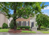 Charming brick home with black shutters, mature trees, and a welcoming front porch at 327 Commons Walk Cir, Cary, NC 27519