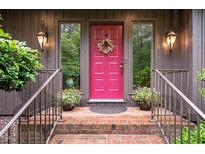 Inviting front entrance with pink door, brick steps, and decorative sidelights and plants at 3285 Edinburgh Dr, Sanford, NC 27332