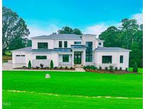 Stunning modern home boasts a manicured lawn, stone accents, and a grand entrance, creating instant curb appeal at 4 Rainforest Pl, Apex, NC 27523