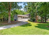 Charming two-story home features a well-manicured lawn, lush trees, and a long driveway leading to a garage at 4001 Pin Oak Rd, Raleigh, NC 27604