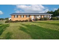 Charming brick home with a metal roof, manicured lawn, and mature landscaping at 4536 Massey Rd, Zebulon, NC 27597