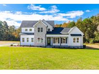 Beautiful two-story home with a combination of white siding and stone accents plus a large manicured front lawn at 50 Farmstead Ct, Wendell, NC 27591