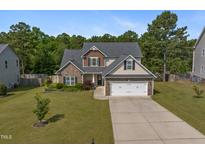 Charming two-story home with stone accents, lush landscaping, and a two-car garage at 550 Spring Flowers Dr, Cameron, NC 28326